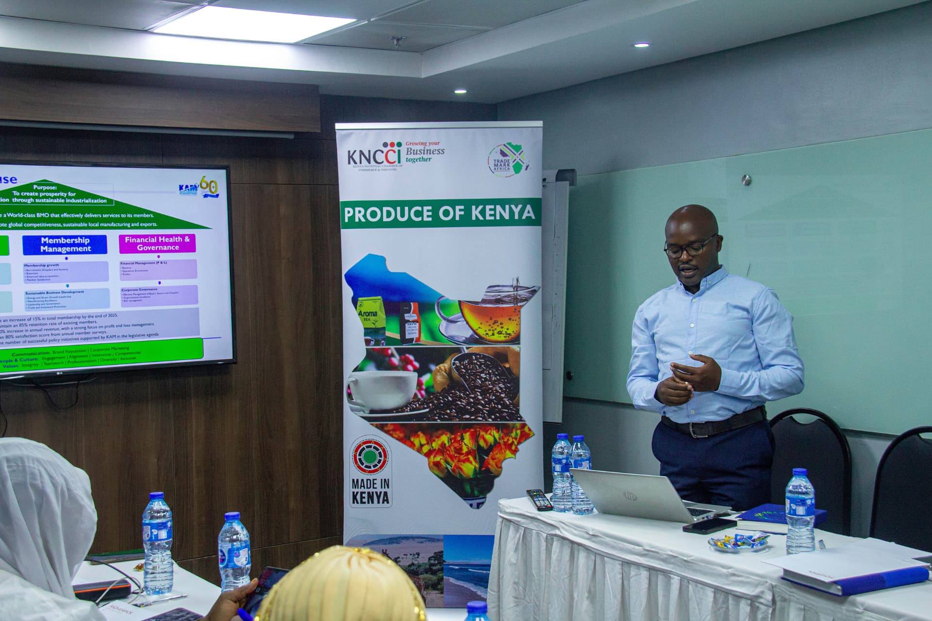 Kenya Association of Manufacturers representative presenting beside the Produce of Kenya banner